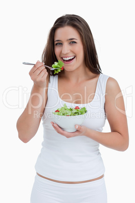Smiling young woman eating a salad