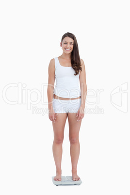 Smiling woman looking at the camera while standing on weighing s