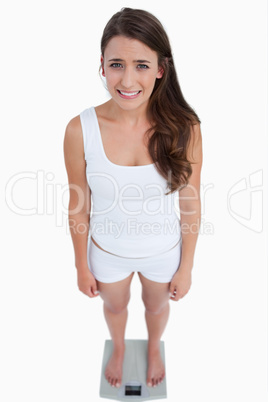 Sad brunette woman weighing herself