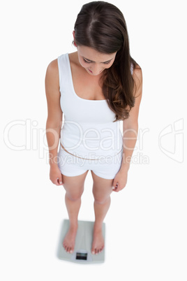 High angle view of a brunette woman weighing herself