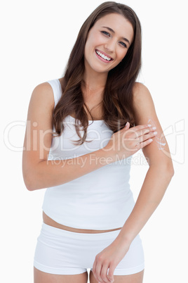 Smiling woman looking at the camera while applying cream on her