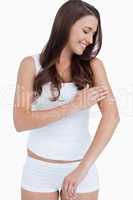 Smiling woman looking at her arm while applying cream