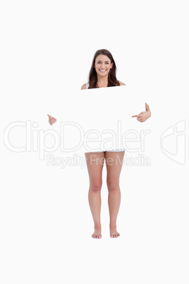 Smiling woman pointing a blank poster