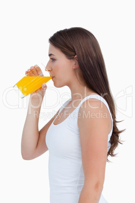 Side view of an attractive brunette drinking an orange juice