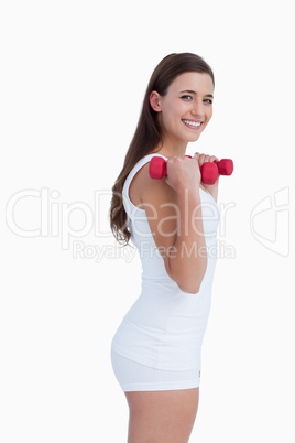 Side view of a young brunette holding dumbbells