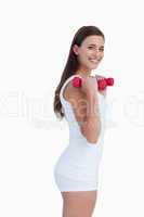 Side view of a young brunette holding dumbbells