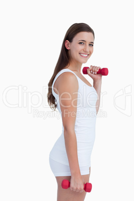 Side view of smiling woman holding dumbbells