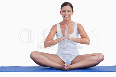 Young woman joining her hands while sitting on a mat