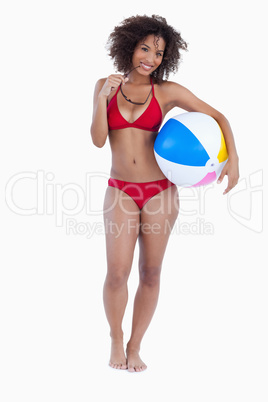 Smiling woman holding a beach ball and sunglasses