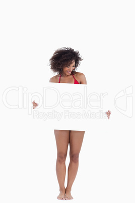 Smiling woman holding a blank poster while wearing a swimsuit