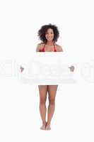 Smiling woman in beachwear holding a blank poster