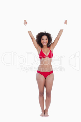 Smiling woman standing upright while holding a blank poster abov