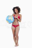 Smiling woman pointing a globe beach ball