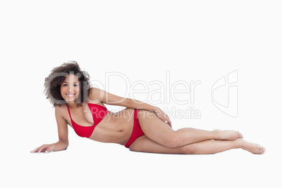 Smiling brunette lying down while looking at the camera