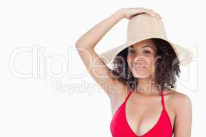 Attractive brunette woman in swimsuit holding her straw hat
