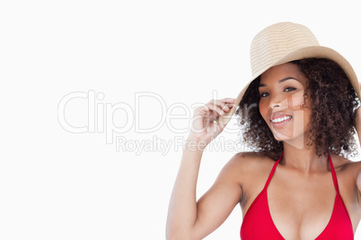 Smiling woman looking at the camera while holding her straw hat