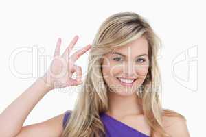 Smiling young blonde woman making the ok sign