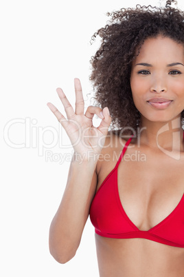 Serious young brunette showing the ok sign