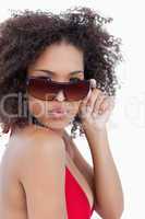 Young woman puckering her lips while holding her sunglasses