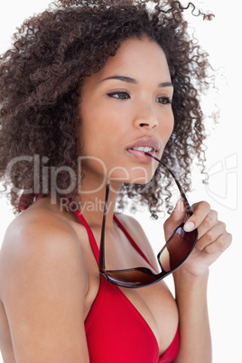 Young woman looking away while holding her sunglasses