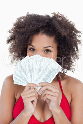 Brunette woman hiding her face behind a fan of notes