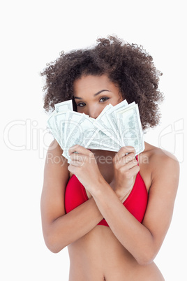 Brunette woman hiding her face behind two fans of notes