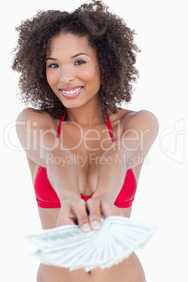 Smiling brunette woman standing upright while holding bank notes