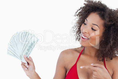 Smiling brunette woman pointing a fan of dollar notes
