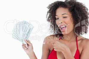 Young woman blinking an eye while holding a fan of notes