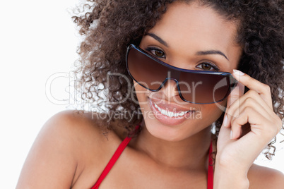 Smiling young brunette looking over her sunglasses