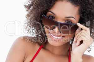 Smiling young brunette looking over her sunglasses