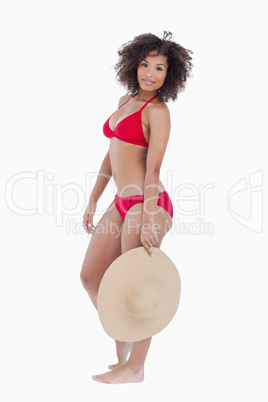 Young woman holding her straw hat while looking at the camera