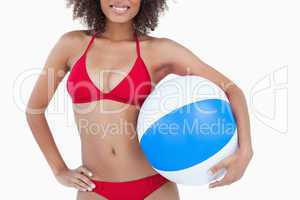 Smiling brunette woman holding a beach ball
