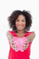 Pink piggy bank being held by a brunette woman