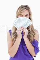 Blonde woman blinking an eye while holding bank notes