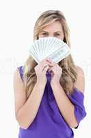 Blonde woman hiding her face behind a fan of notes