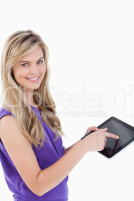 Happy blonde woman looking at the camera while using her tablet