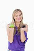 Smiling blonde woman holding a fruit and a muffin