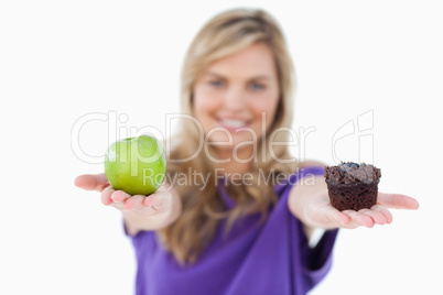 A green apple and a muffin being held by a young woman