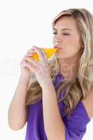 Young blonde woman drinking an orange juice