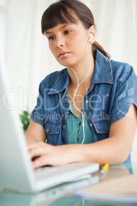 Female student doing her homework with music