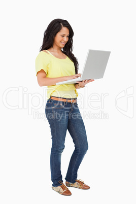 Smiling Latin student standing with a laptop