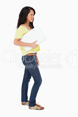 Side view of a beautiful Latin student holding a laptop