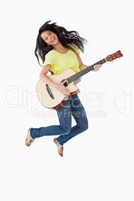 Young Latino woman holding a guitar while jumping