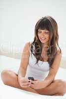 Crossed-legged young woman smiling while reading a text message