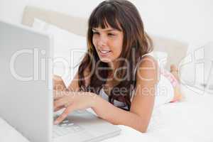 Young woman in pajama chatting on a laptop