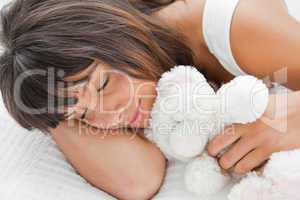 Beautiful young woman sleeping with a teddy bear