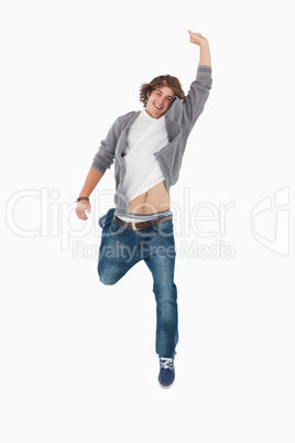 Male student posing by jumping with a raised arm