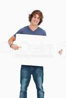 Male student posing while holding and pointing a white board