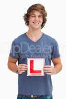 Smiling young man holding a learner driver sign